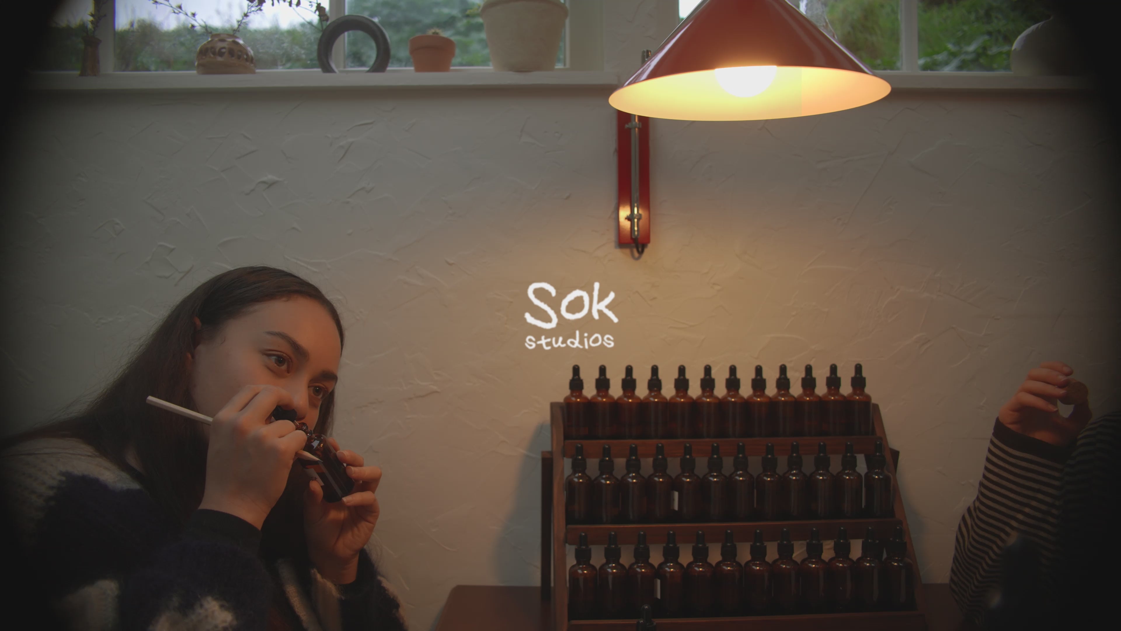 Two guests at SOK Studios perfume workshop chatting at a table with amber fragrance bottles under a warm lamp